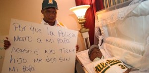 El jovencito Melvin Peguero cuestiona en un cartel, junto al féretro de su padre Agustín Peguero, porqué le dieron muerte