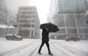 A man crosses a street as snow continues to fall in Charlotte