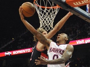 Jeff Teague (0), de los Hawks de Atlanta, encesta bajo el aro en contra de Robin López (42), de los Trail Blazers de Portland, en la primera mitad del juego de NBA del jueves 27 de marzo de 2014, en Atlanta. Los Trail Blazers ganaron 100-85. 