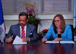 Momentos en que el presidente de la Junta Central Electoral, doctor Roberto Rosario Márquez y la directora de Pasaportes, Licenciada Iris Guaba, firman el convenio.