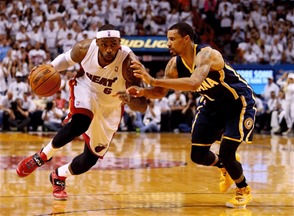 LeBron James se mueve de manera veloz con la pelota en busca de dos puntos, mientras recibe el acoso de George Hills, de los Pacers.