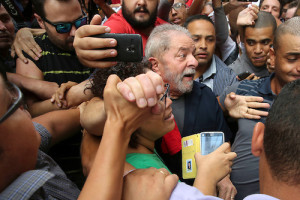 BRA158. SÃO PAULO (BRASIL), 04/03/2016.- El expresidente brasileño Luiz Inácio Lula da Silva (c) saluda a simpatizantes hoy, viernes 4 de marzo de 2016, afuera de la sede del partido de los trabajadores en Sao Paulo (Brasil). Luiz Inácio Lula da Silva afirmó hoy que se sintió "prisionero" cuando la Policía Federal allanó esta mañana su casa para llevarlo a una comisaría, donde prestó declaración durante más de tres horas. El ex jefe de Estado dijo estar "indignado" por la llegada de los agentes de la policía y tildó de "lamentable" la actuación del "Poder Judicial", en un discurso que pronunció en la sede de la dirección nacional del Partido de los Trabajadores (PT). EFE/SEBASTIÃO MOREIRA